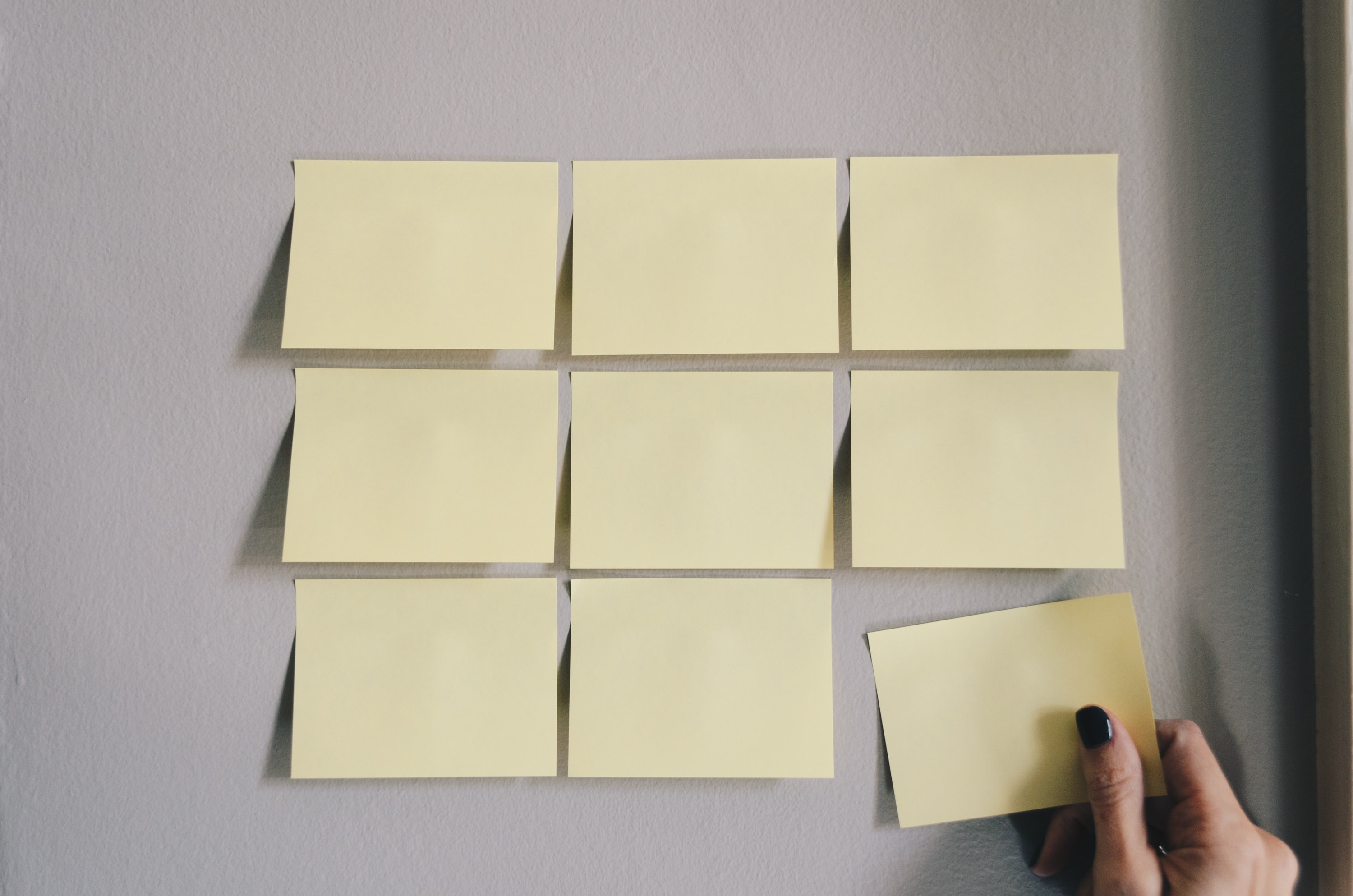 Nine yellow sticky notes on a wall