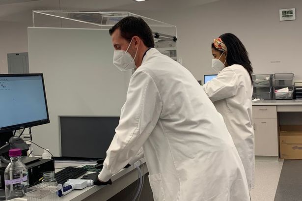 Two people in laboratory coats and masks