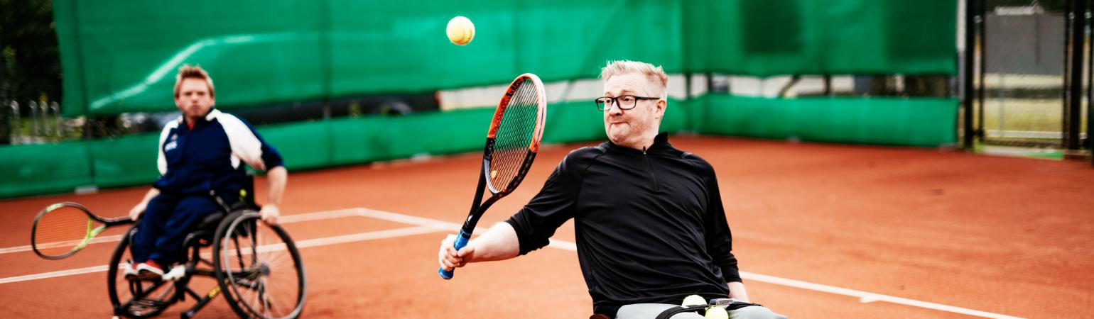 Two people in wheelchairs playing tennis