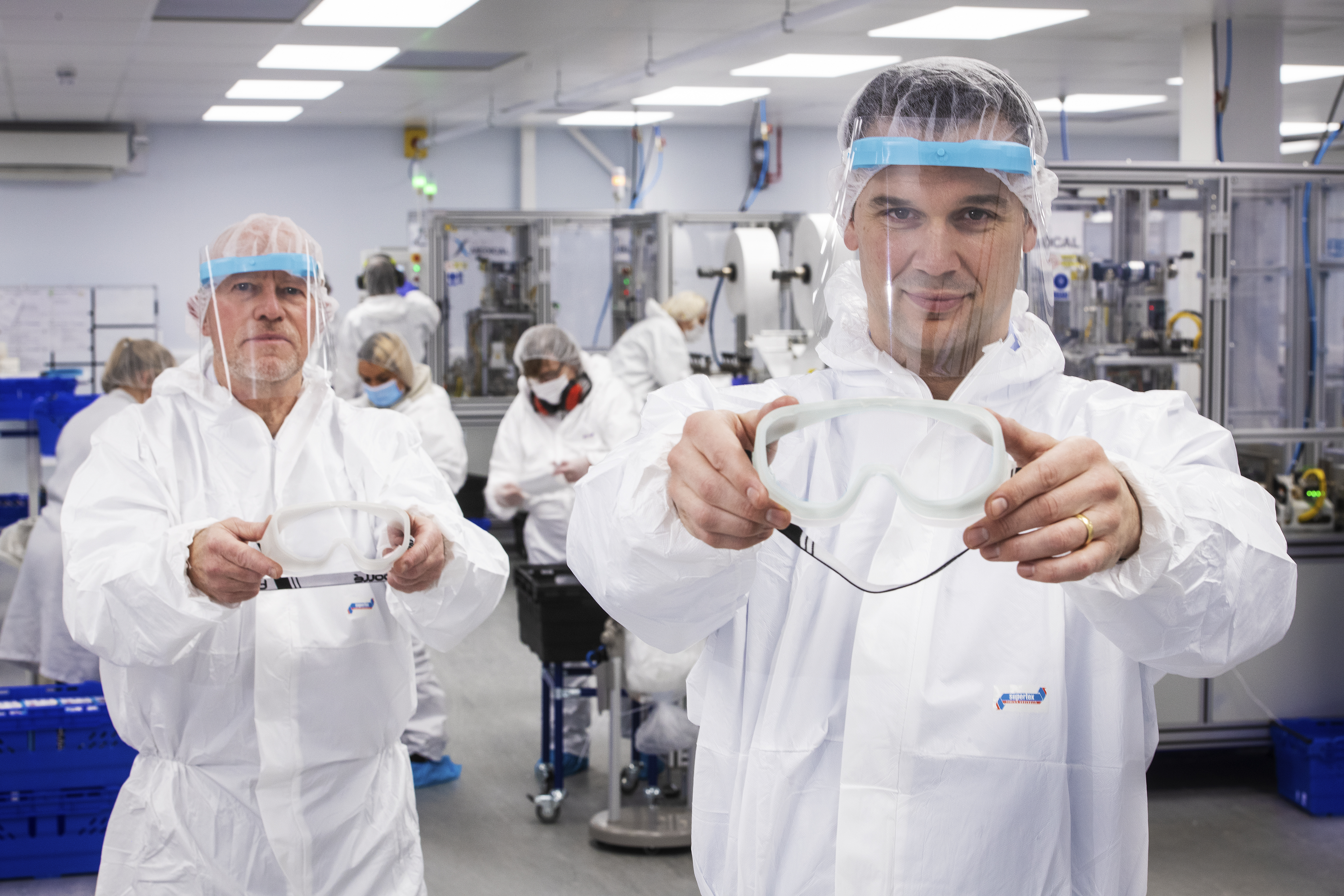 2 people in PPE holding product