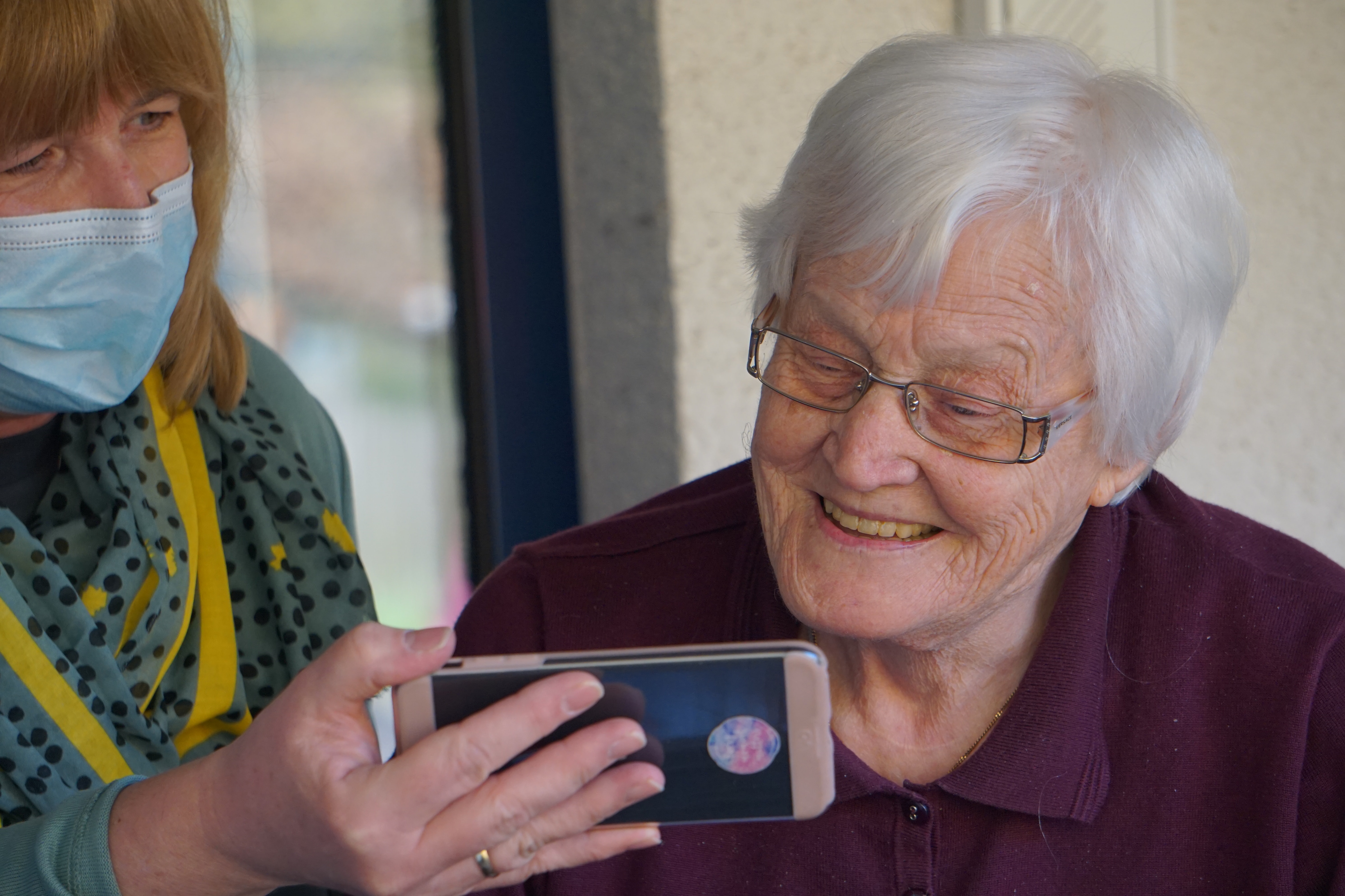 Social care professional with woman looking at a phone