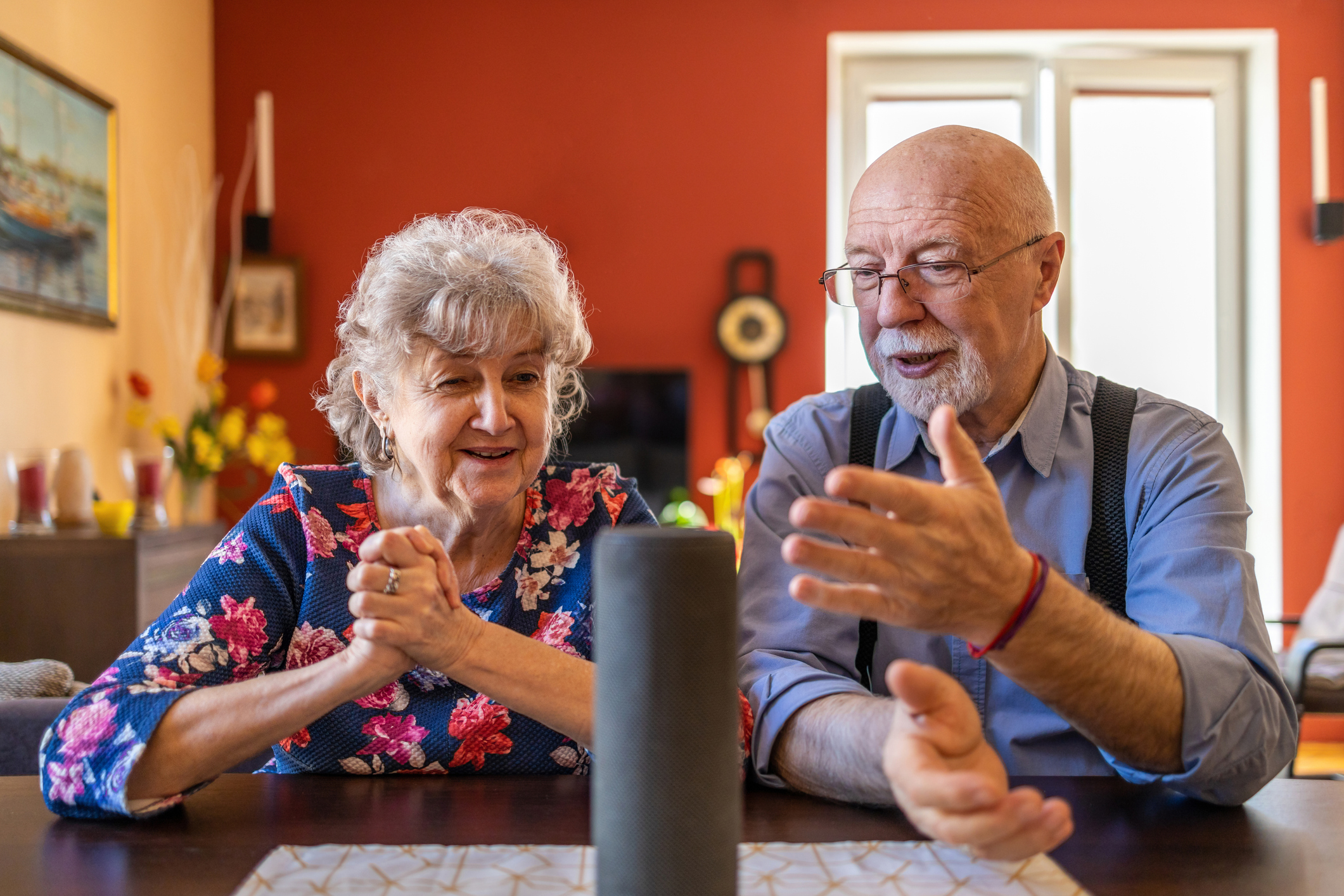 Excited senior couple using a Virtual Assistant at home