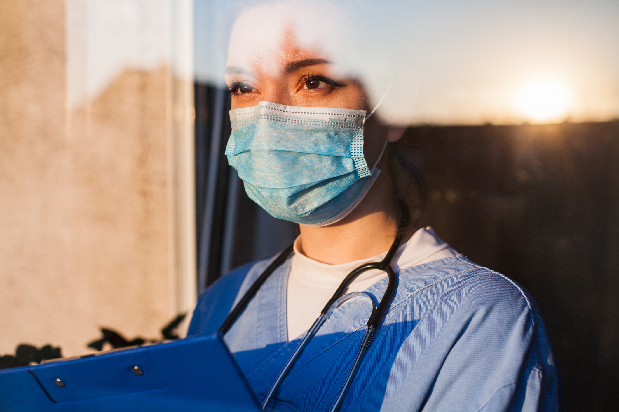 medical worker wearing PPE looking out of hospital window.