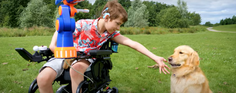 Harri in his wheelchair, playing with his dog.