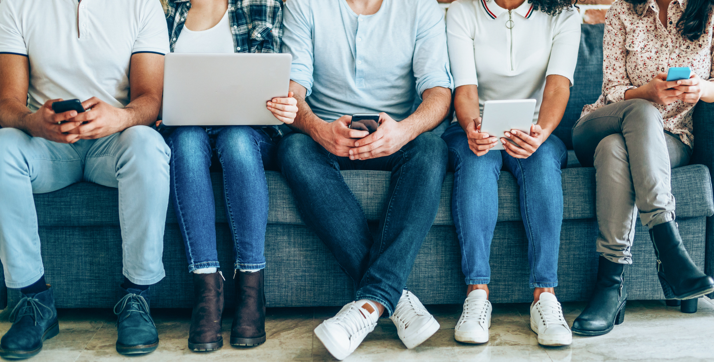 People sat in a row using laptops, smartphones, and tablets