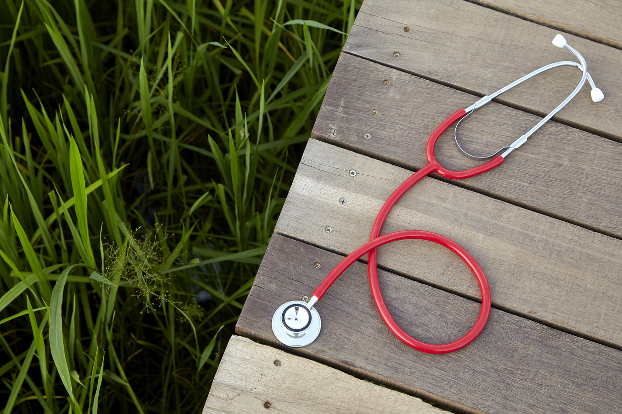 A red stethoscope outdoors next to grass