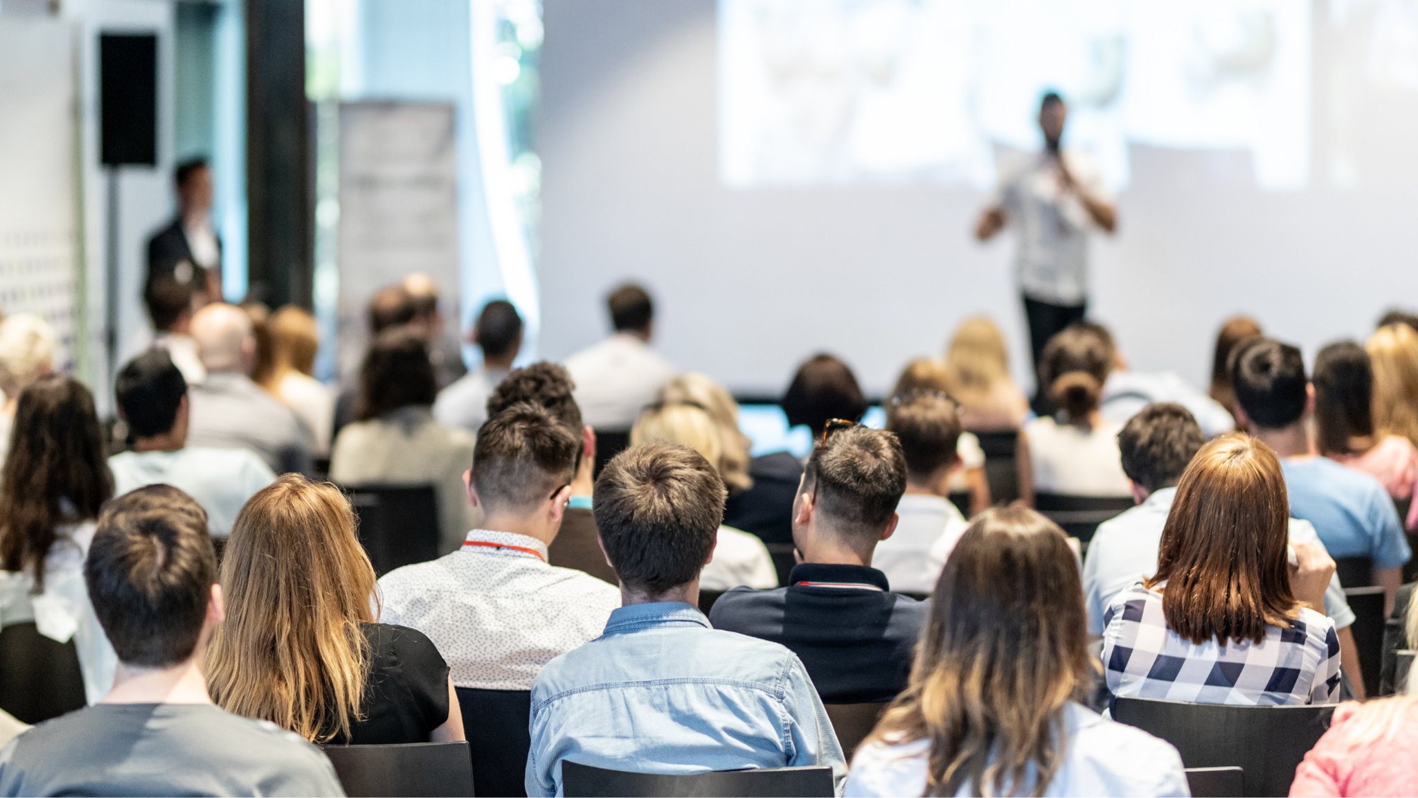 A group of people sitting and listening to a man speaking at a conference