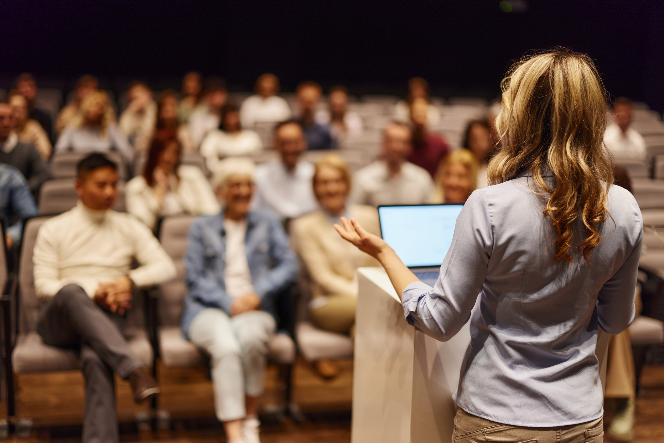 A blonde woman speaking to a lecture hall full of people