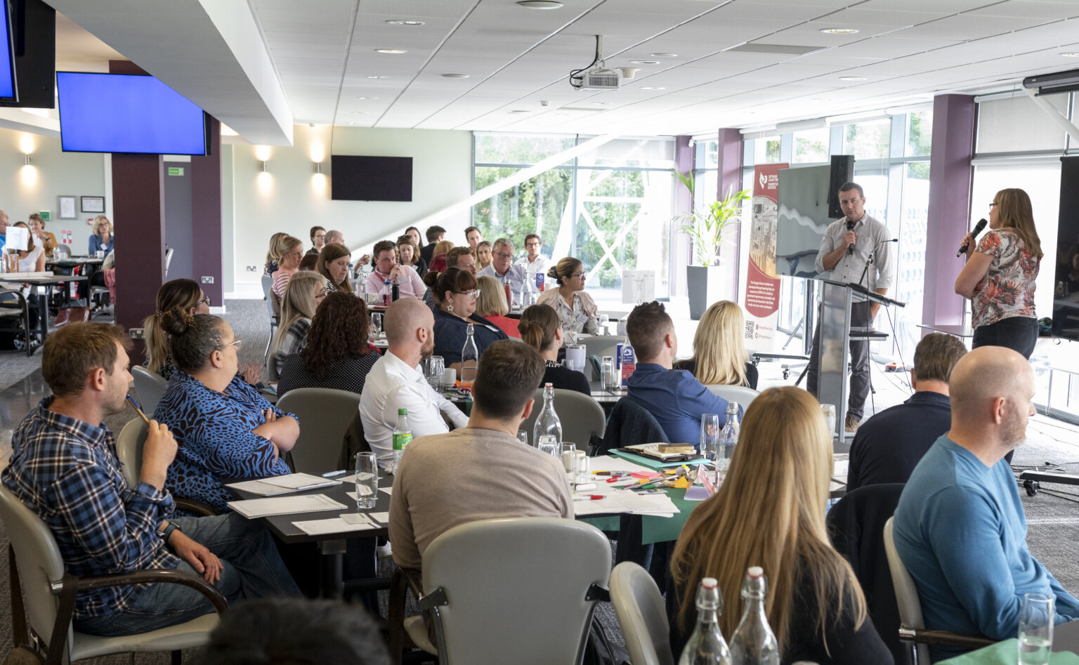 Many people sitting and listening to a man talking at an event