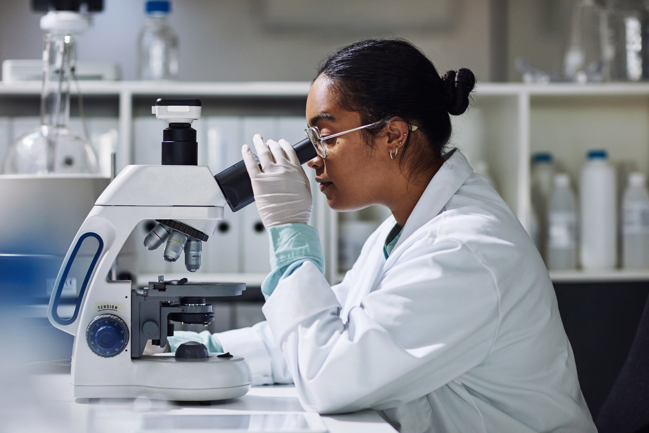 A scientist in a lab, looking through a microscope