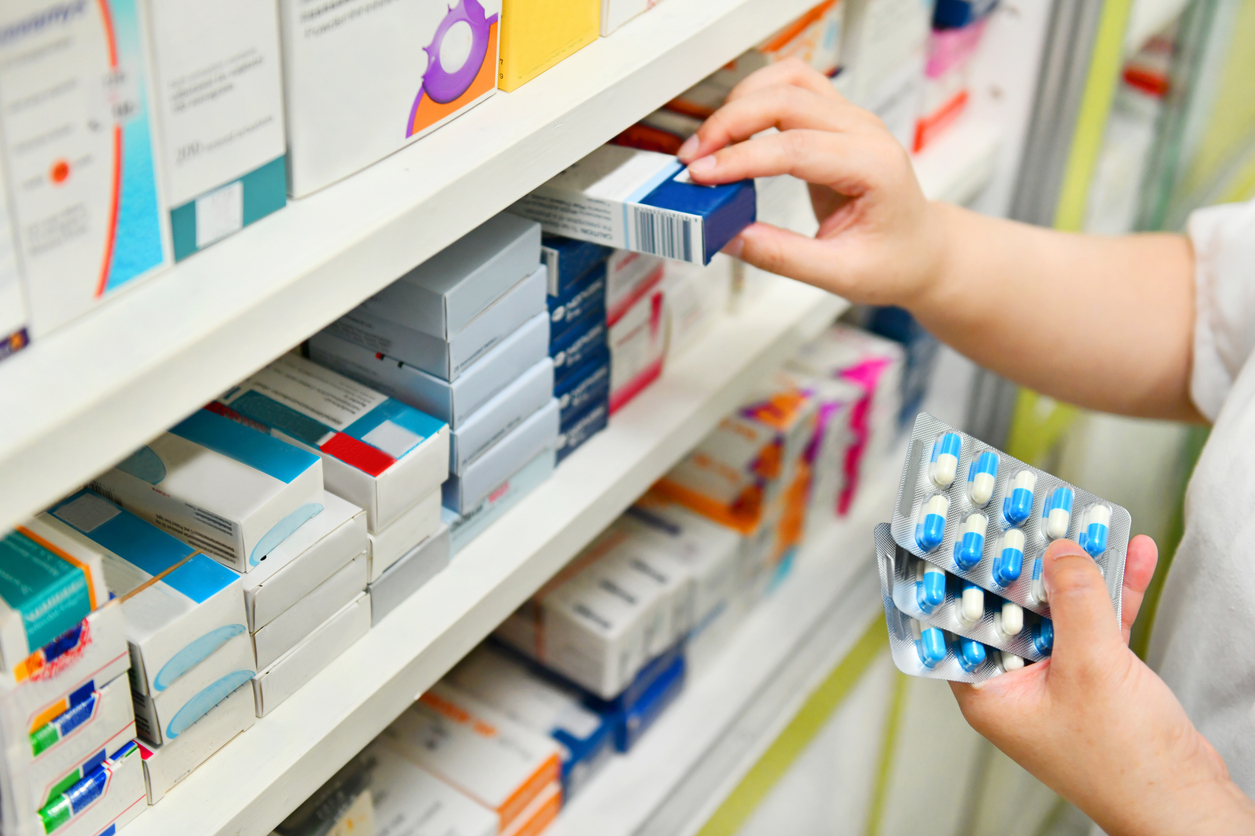 A pharmacist putting boxes of medicine on a shelf