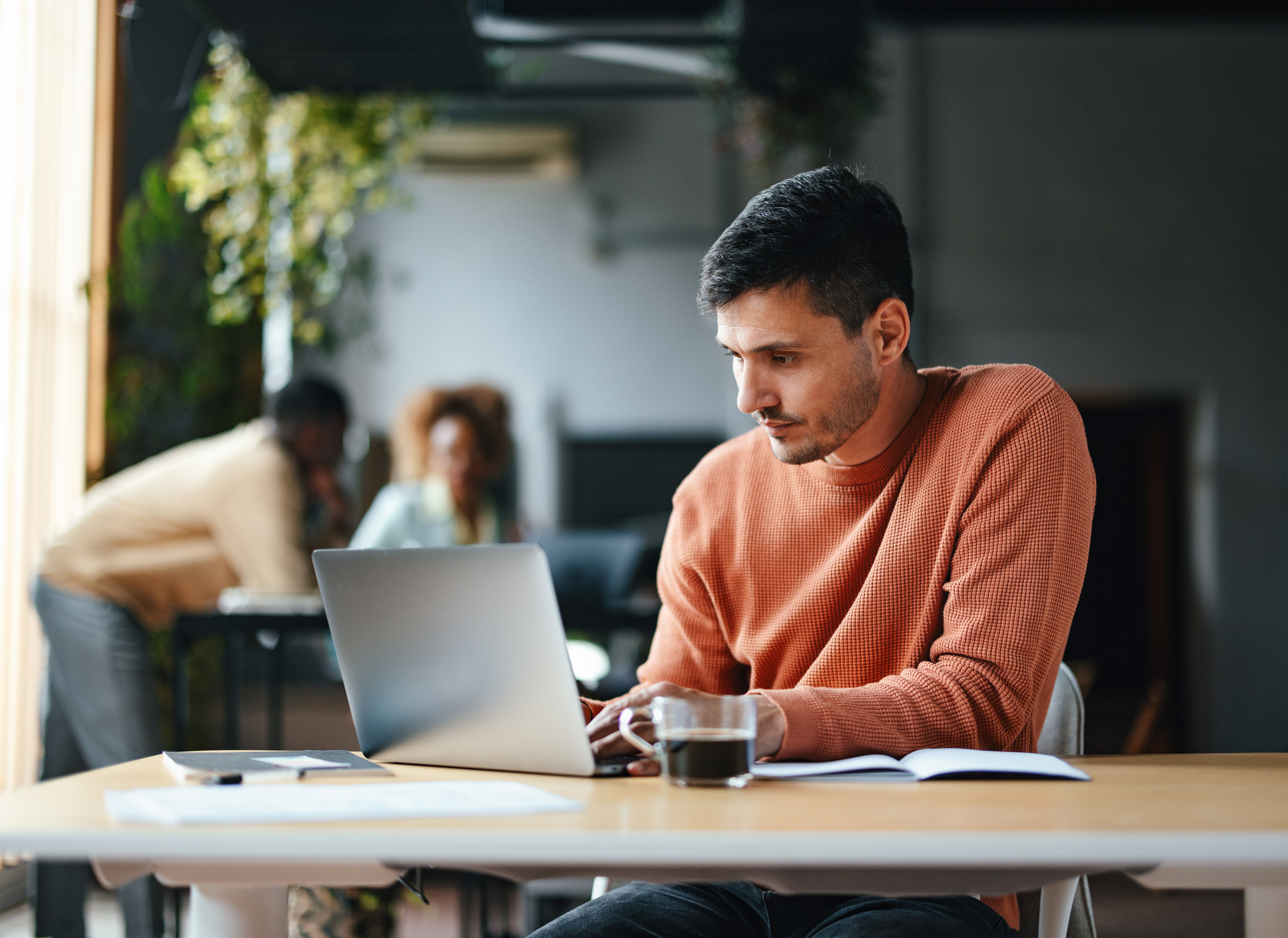 A man in an orange jumper looking at a laptop
