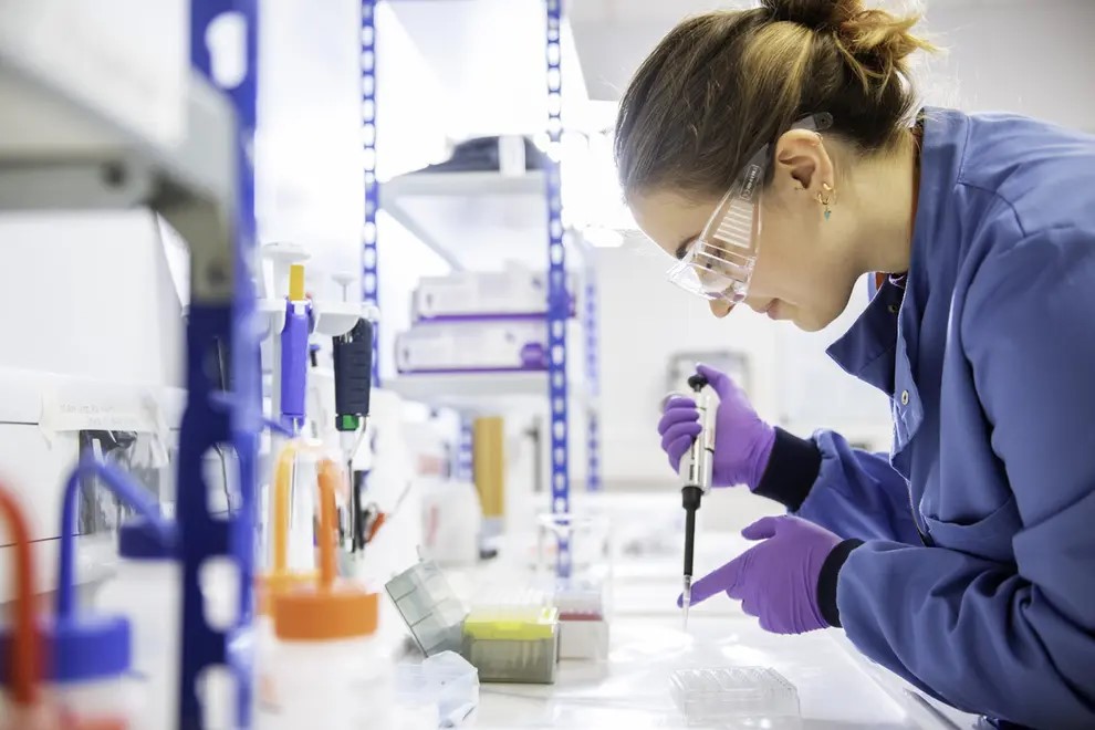 A scientist in a lab with a pipette