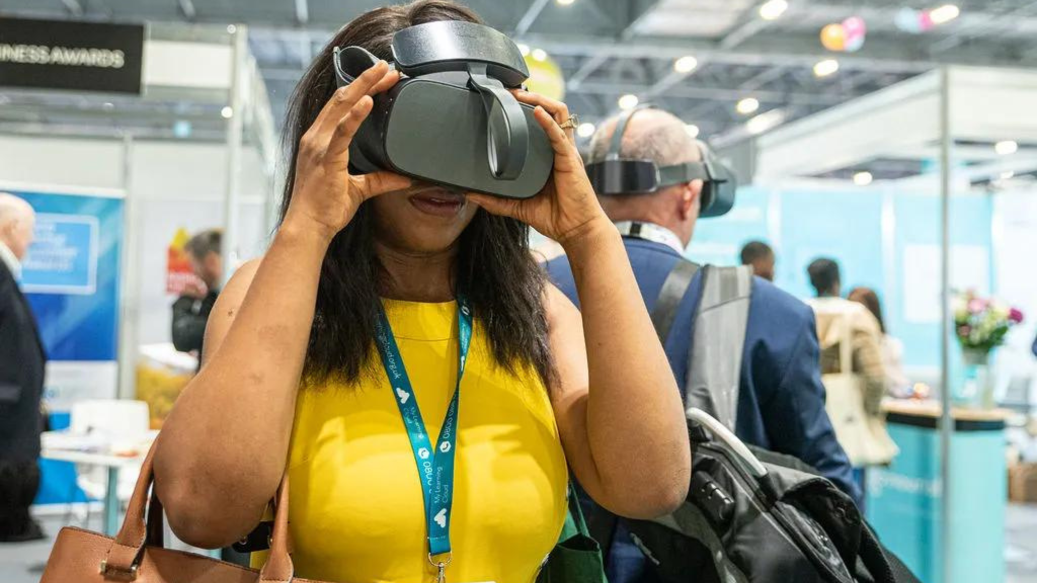 A woman in a yellow top, wearing a VR headset at an event