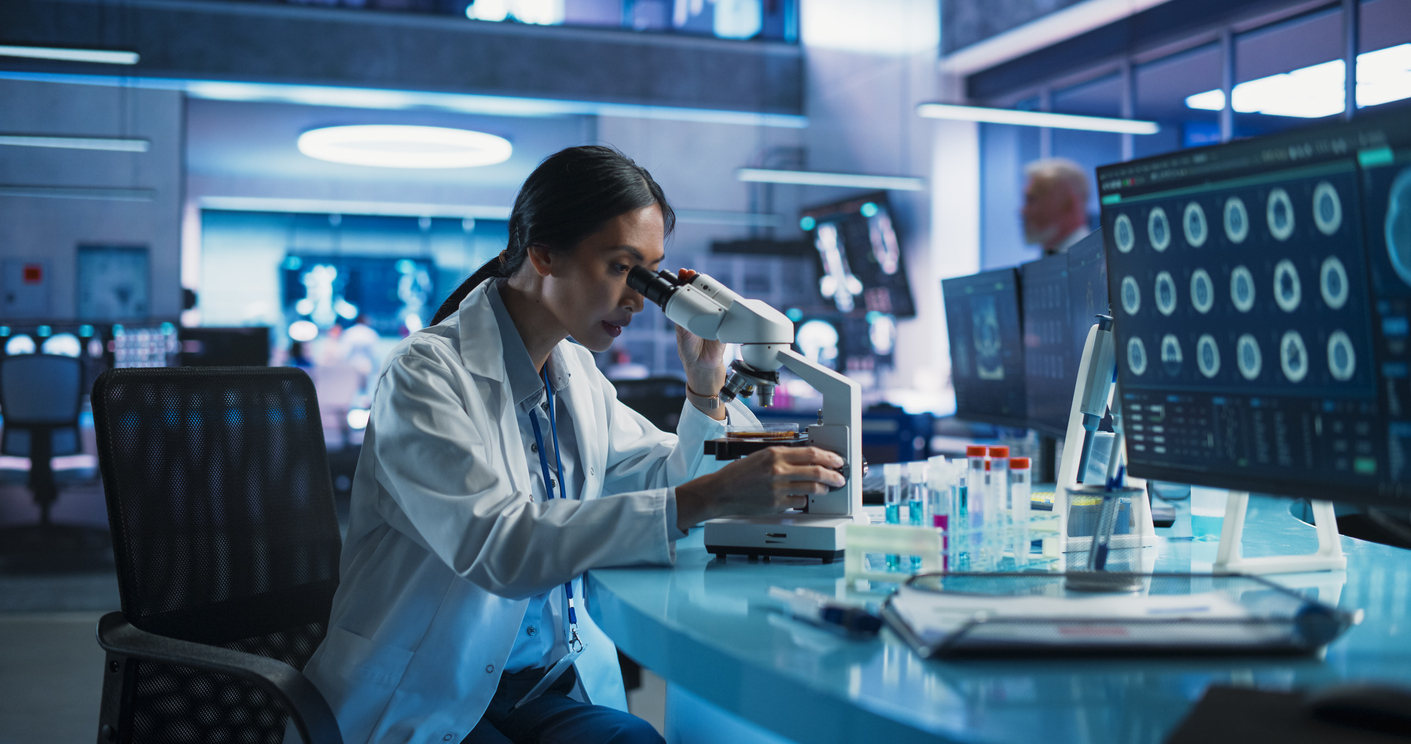 A woman in a lab looking through a microscope