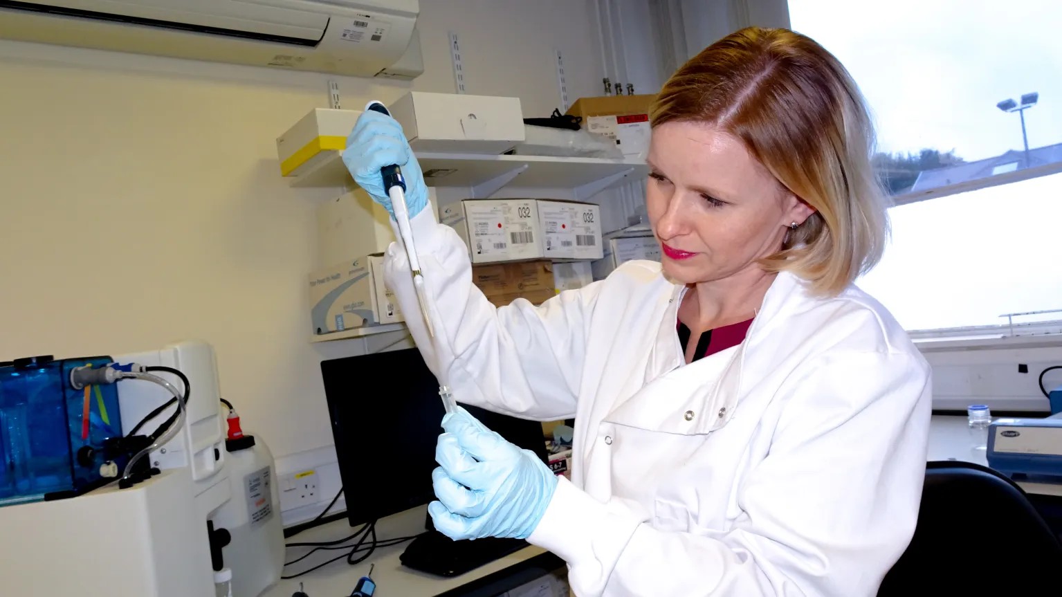 Woman in a lab, holding a pippette.