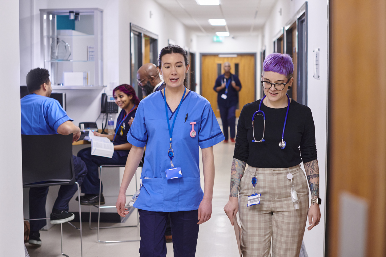 Two women walking towards the camera in a hospital.