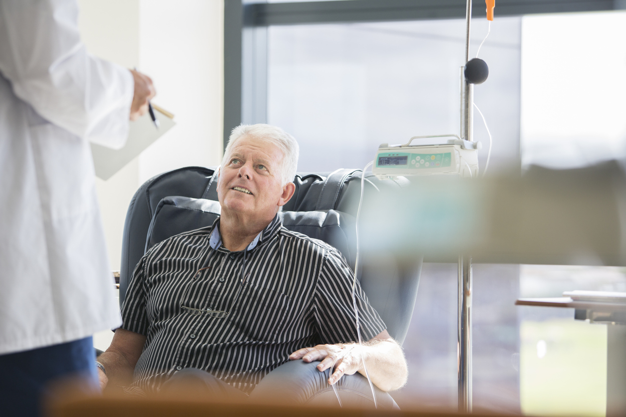 Doctor talking to patient receiving medical treatment in hospital ward