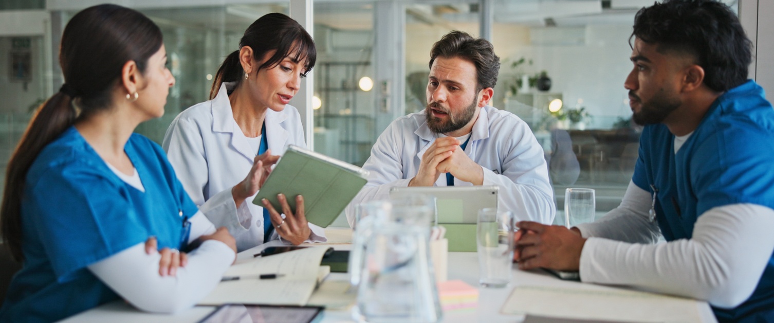 Four health professionals sitting around a table. They are mid discussion.