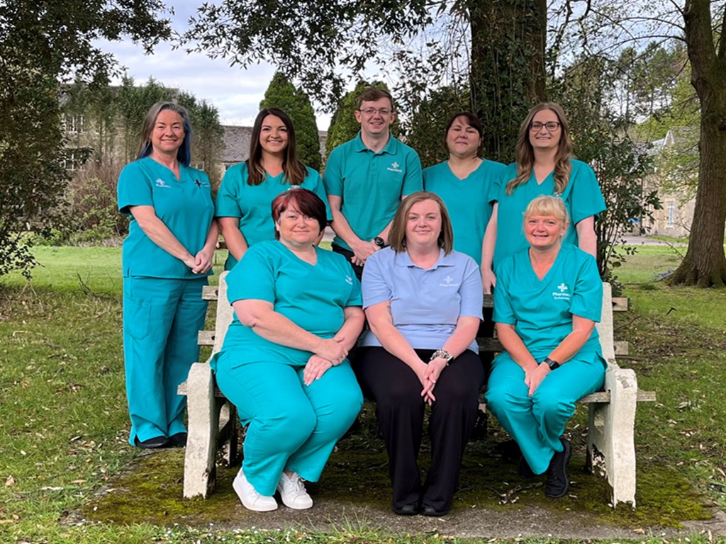 Bridgend project team sitting on a bench, smiling at the camera.