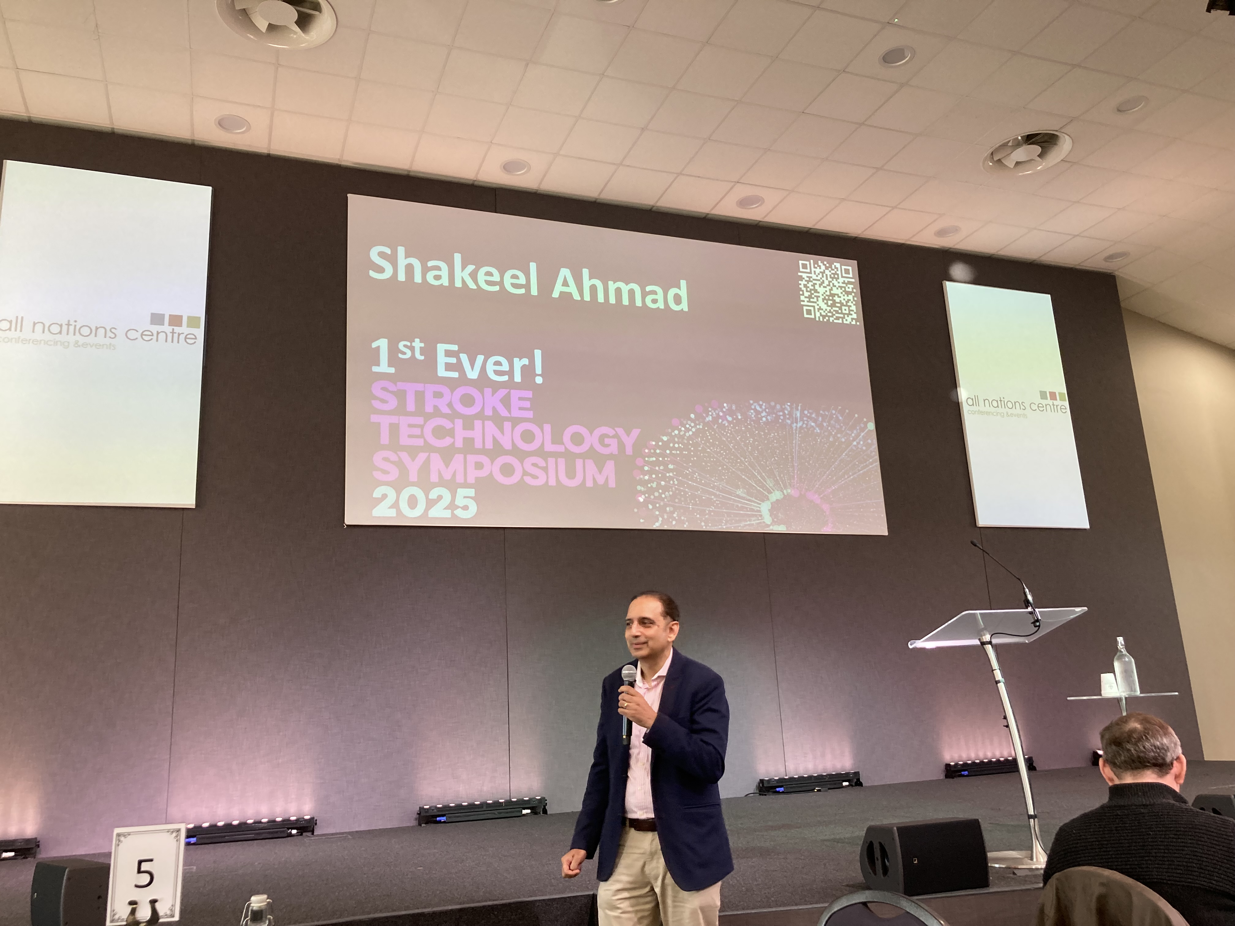 Man standing in front of stage with a microphone.