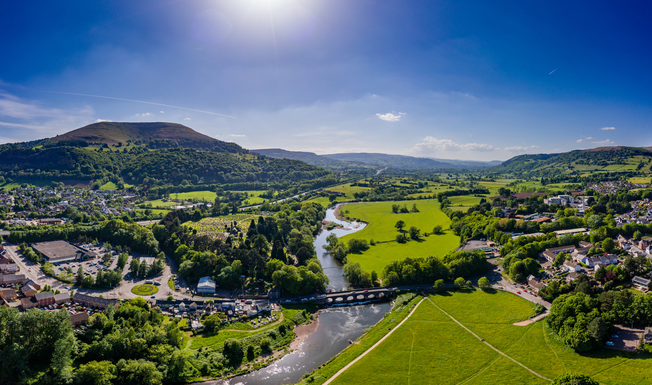 birds-eye-view of Abergavenny, Wales. The sun is shining, the grass is green and the sky is blue.