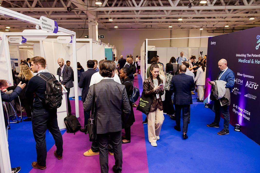 Crowd of people walking through a conference exhibition space.