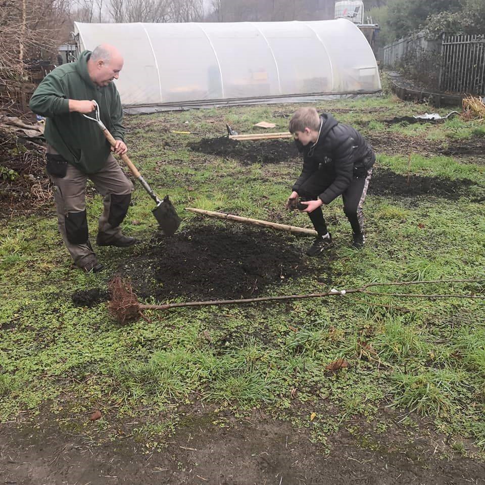 A photo of a man and a young adult digging