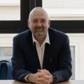 Mike Emery head shot, sitting at a desk with hands crossed 